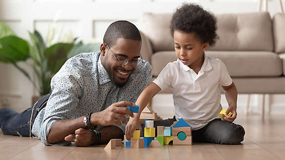Father on the floor playing blocks with his son.