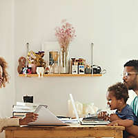 A young couple sitting at the table reviewing paperwork with their baby.