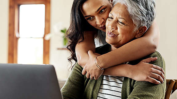 Daughter hugging grandmother at table