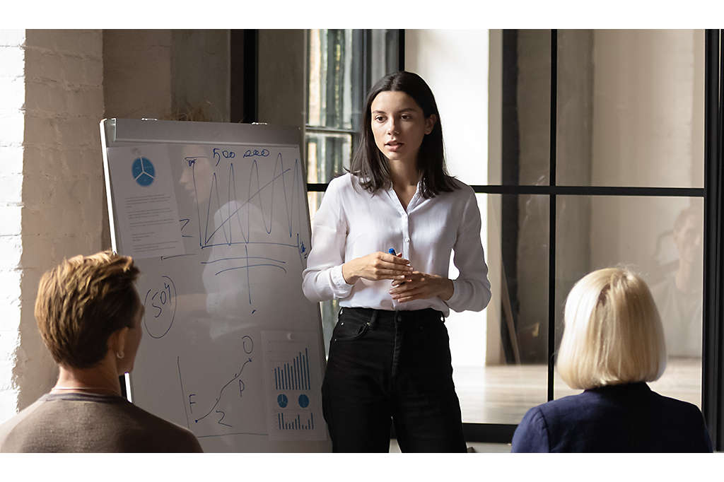 Professional presenting to a group in front of a whiteboard