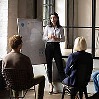 Person presenting to two people sitting down.