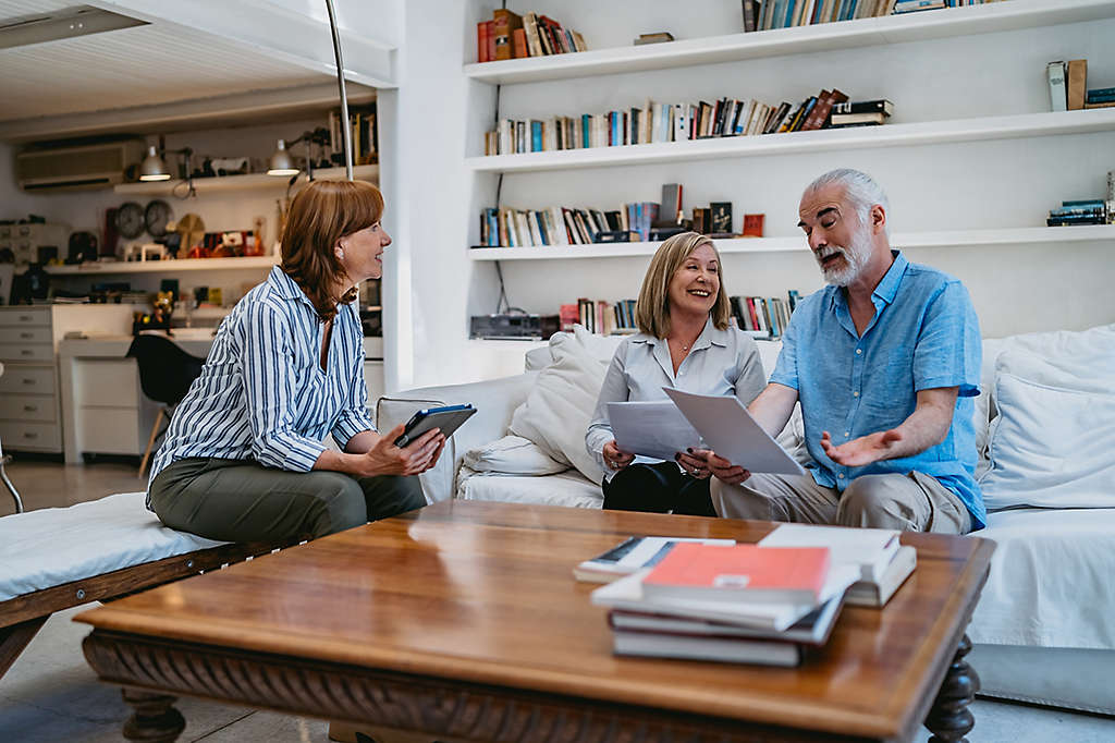 A mature couple at home discussing paperwork with an agent.