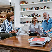 A mature couple at home discussing paperwork with an agent.