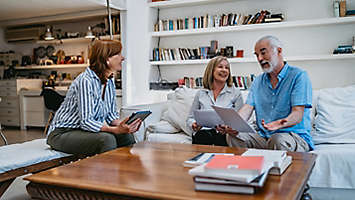 A mature couple at home discussing paperwork with an agent.
