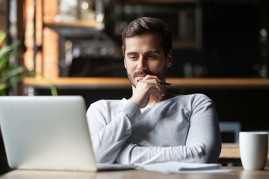 A man sitting at his desk looking at something on his computer.