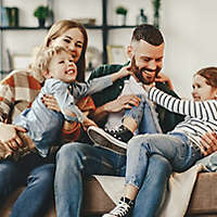 A young family playing together at home on the couch. 