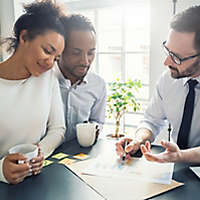 A young couple drinking coffee and looking over paperwork with an agent. 