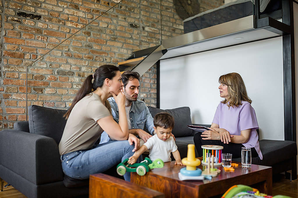 A young family sitting on a couch talking to an agent.