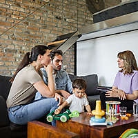 A young family sitting on a couch talking to an agent.