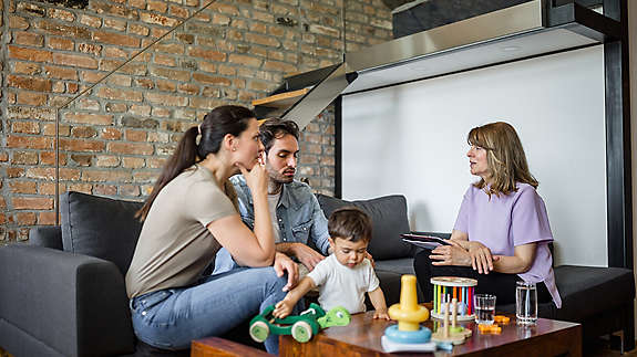 A young family sitting on a couch talking to an agent.