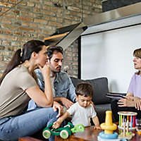A young family sitting on a couch talking to an agent.