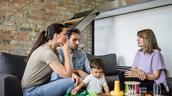 A young family sitting on a couch talking to an agent