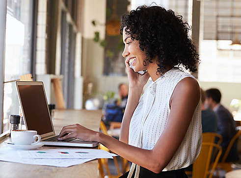 Person working on laptop and talking on the phone