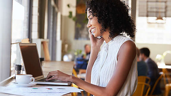 Young woman on the phone and using laptop