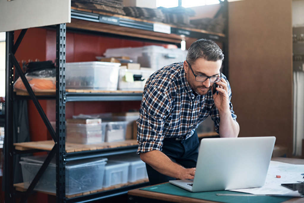 Self-employed business owner checking laptop at his business