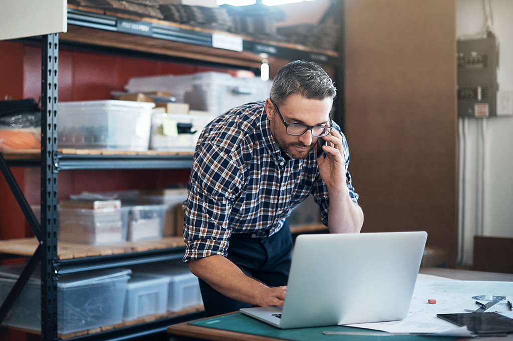 Person working on computer while talking on phone