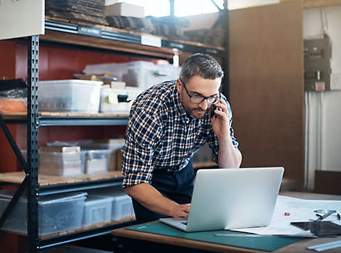 Person working on computer while talking on phone