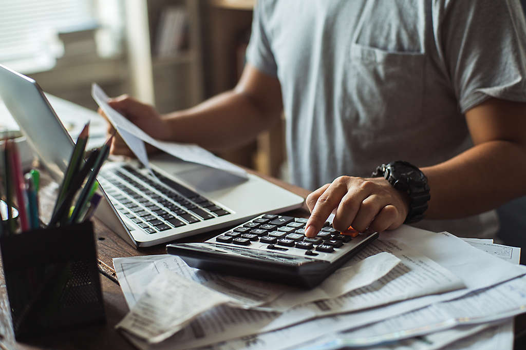 A man at his computer going through bills.