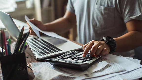 A man at his computer going through bills.