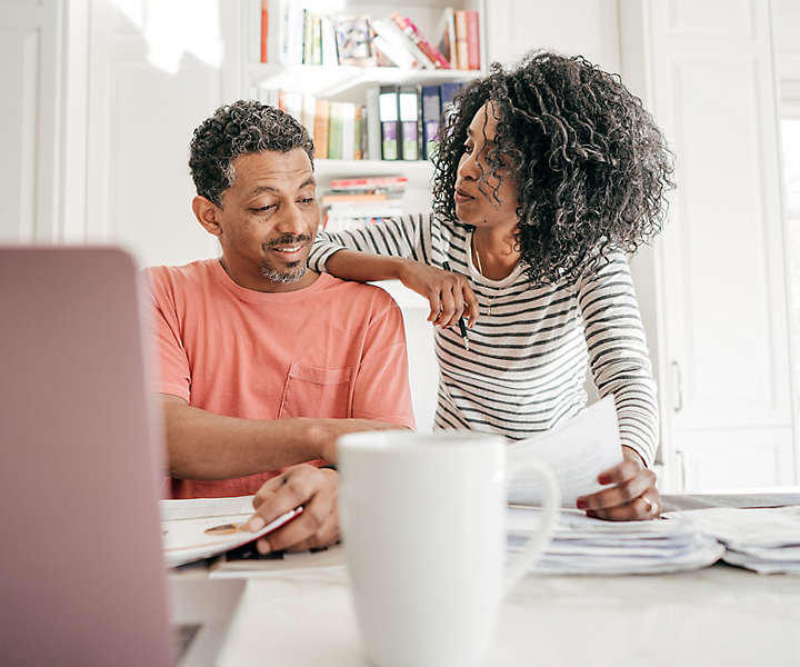 Middle-aged couple reviewing documents in front of a laptop computer