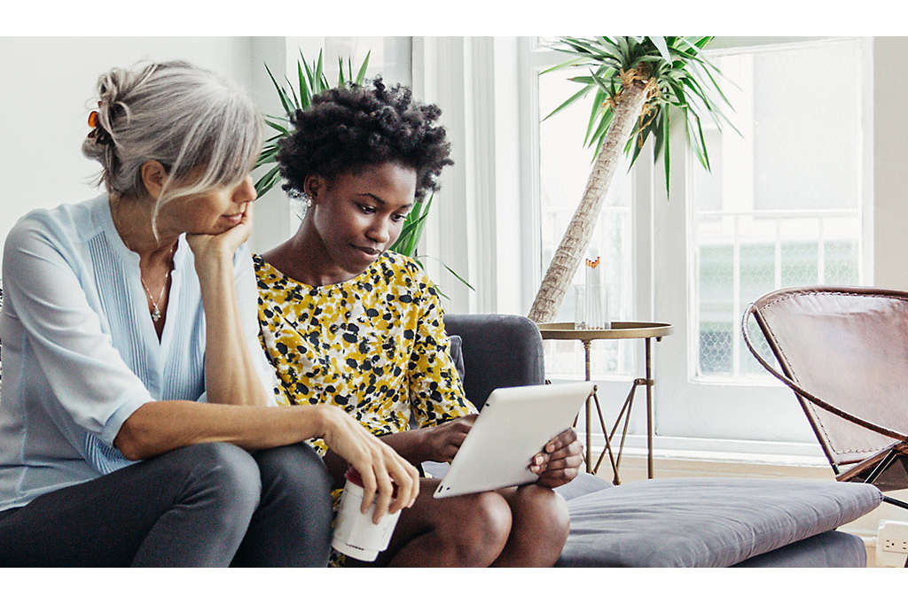 Mother and daughter on couch looking at a computer.