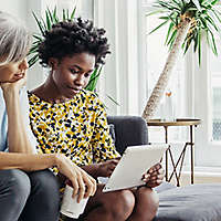 Mother and daughter on couch looking at a computer.
