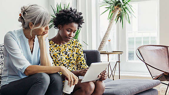 Mother and daughter on couch looking at a computer.