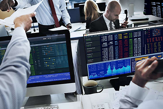 People at work trading and watching stocks on their computers. 