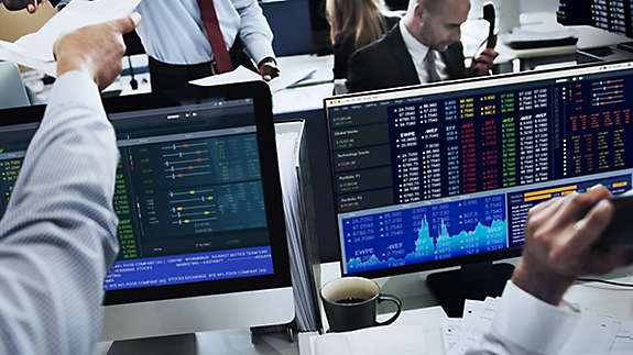 People at work trading and watching stocks on their computers. 