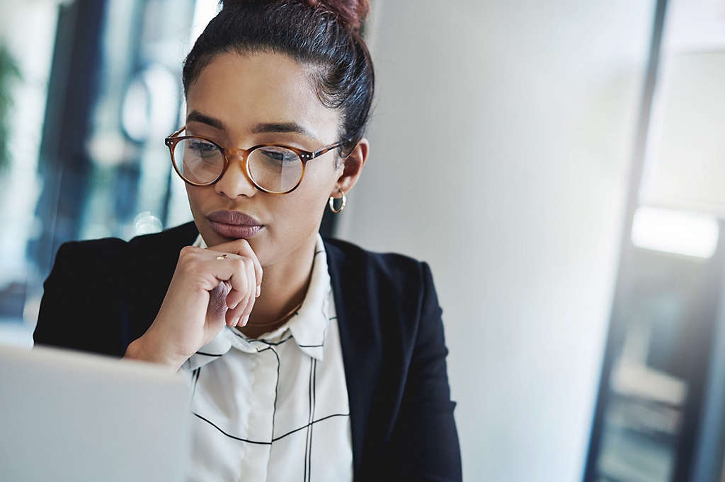 A woman wearing glasses looking at a computer screen.