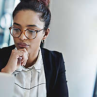 A woman wearing glasses looking at a computer screen. 