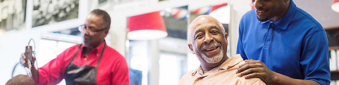 Two men taking care of customers in a barbershop.