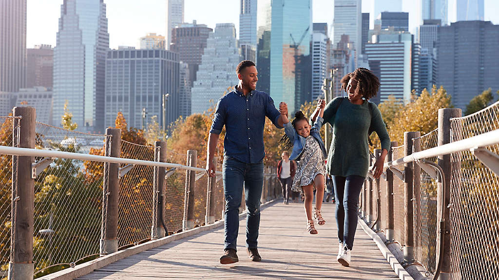 A family walking with their daughter over a bridge