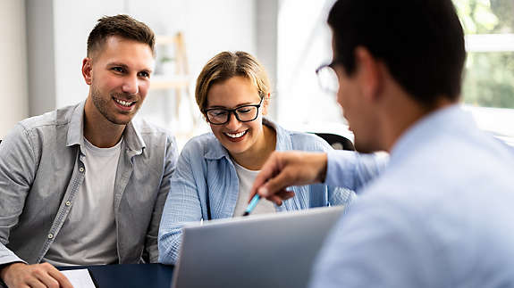An advisor helping clients view their finances on a laptop