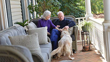 Jill Tigner and Mike Venable sitting on their porch playing with their dog.