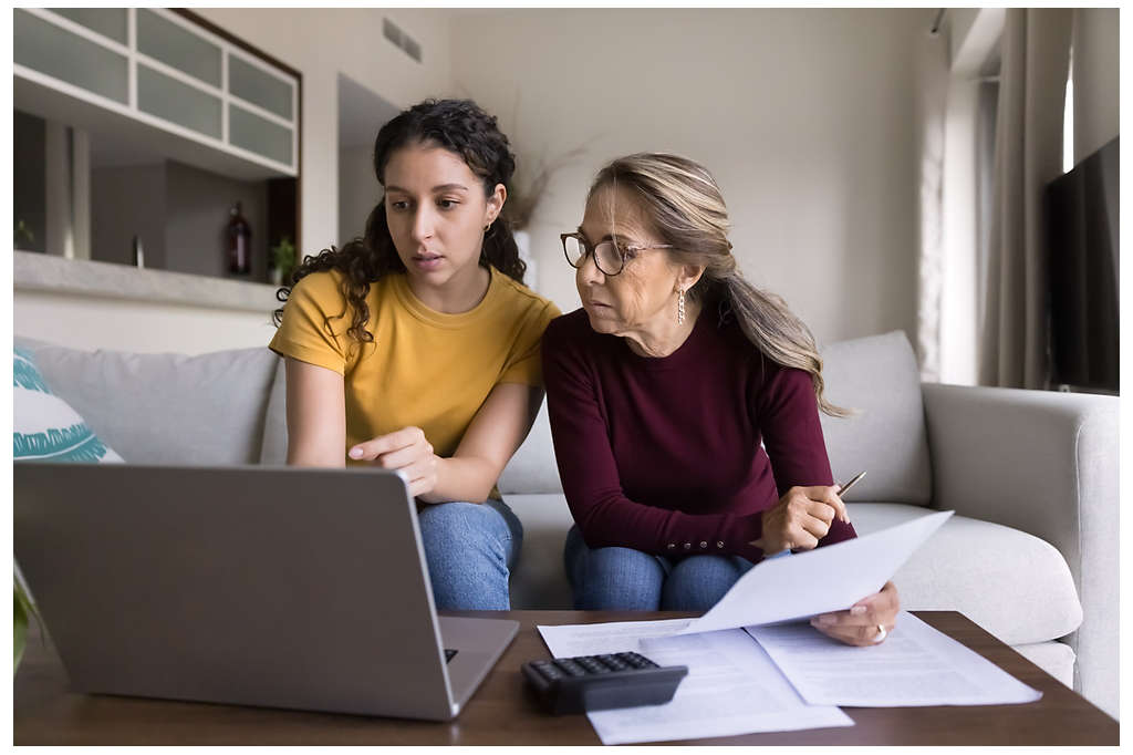 Two women looking at a laptop and paperwork