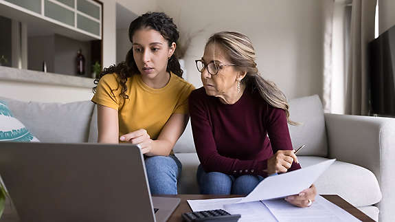 Two women looking at a laptop and paperwork
