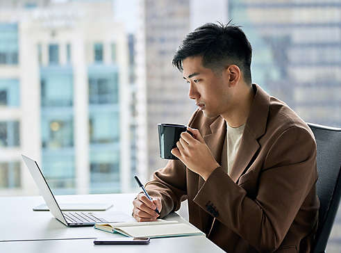 A man using a computer and drinking coffee