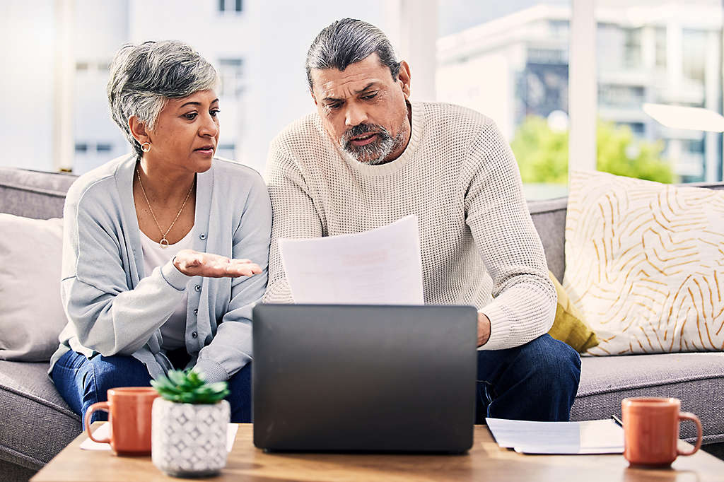 A woman and man reviewing their finances on a laptop looking concerned