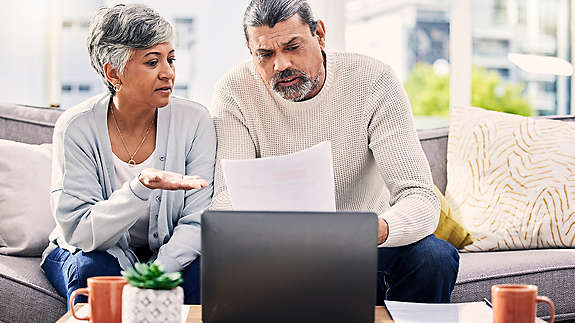 A woman and man reviewing their finances on a laptop looking concerned