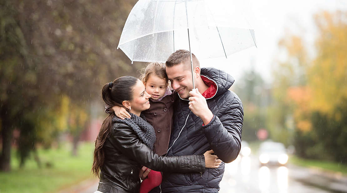Family with daughter under the umbrellas Walk on rainy day.
