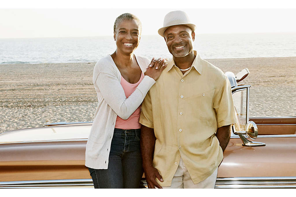 Retired couple on the beach with a classic car