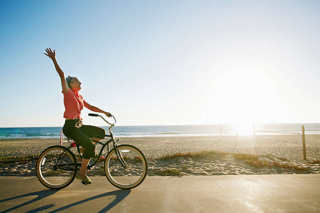 A woman riding her bike by the beach