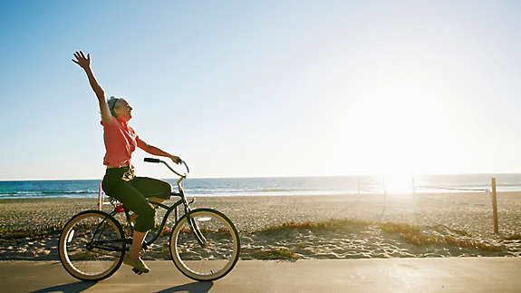 A woman riding her bike by the beach.