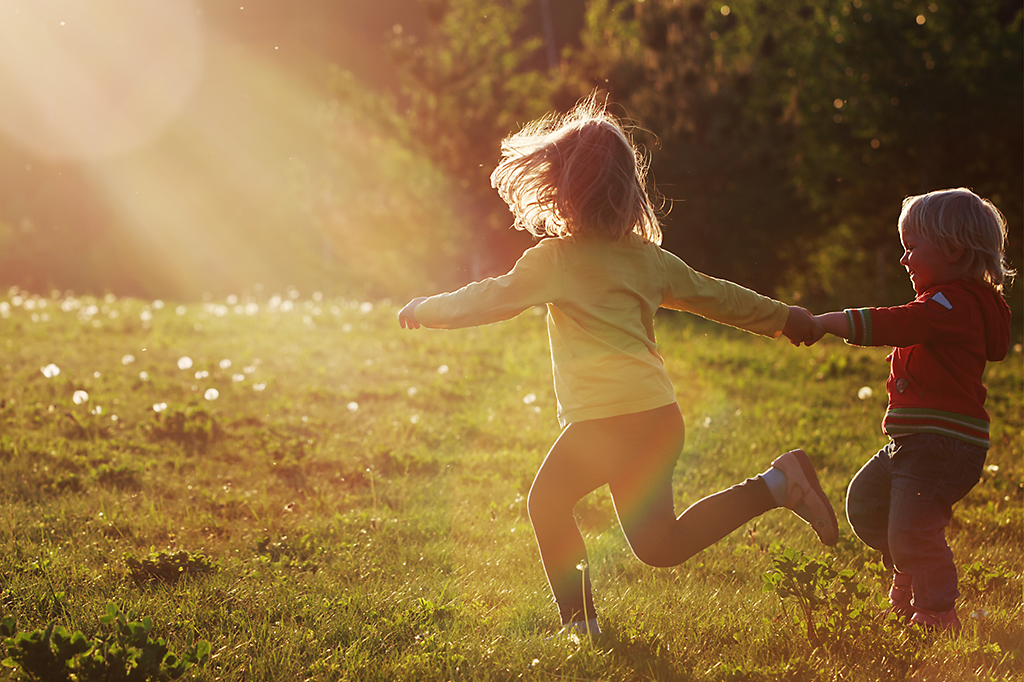 Two kids running through the grass