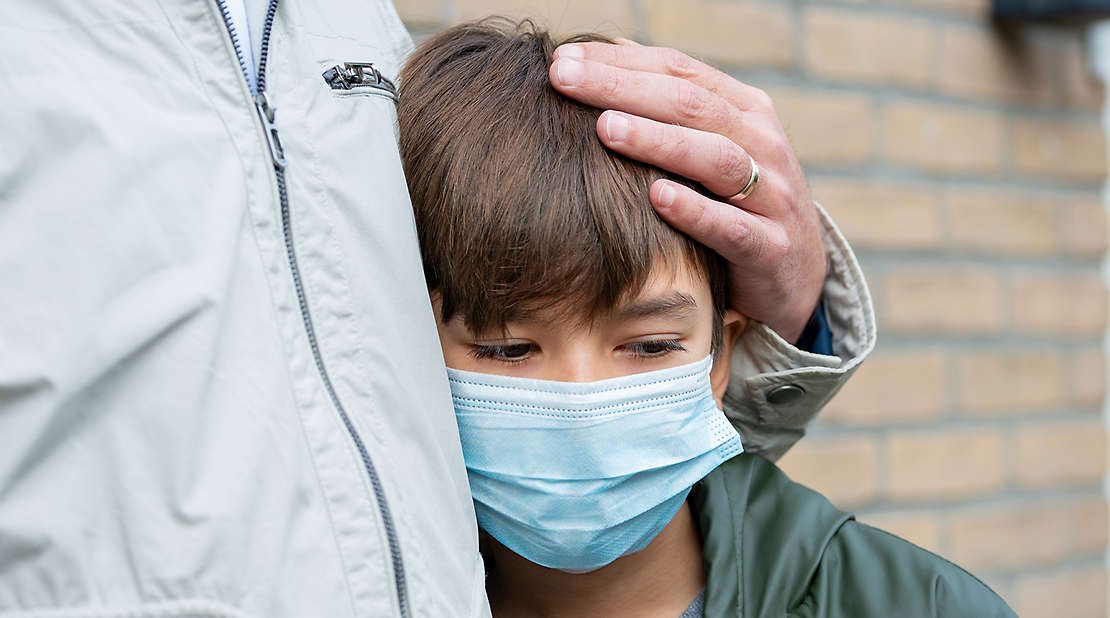 A schoolboy in a medical mask. A father comfort a son, depresson, being sad and lonely because of Coronavirus, Covid-19. love from a father to a son family together