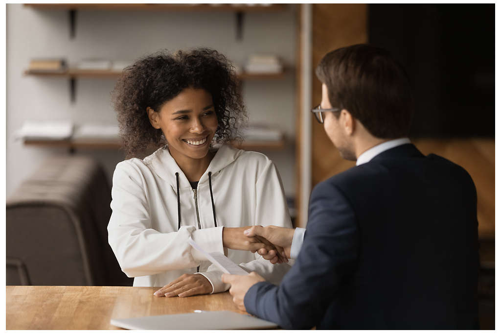 A woman shaking hands with another colleague