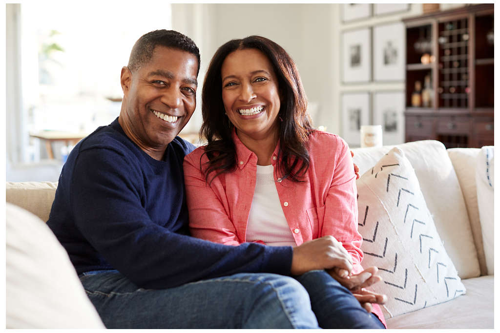 Middle aged African American couple sitting on the couch smiling