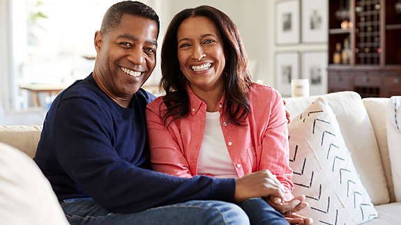 Middle aged African American couple sitting on the couch smiling