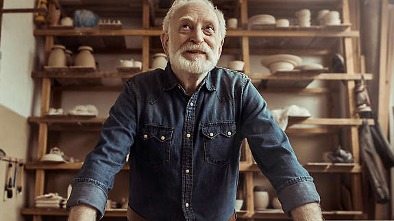 Elderly man smiling in a pottery studio.